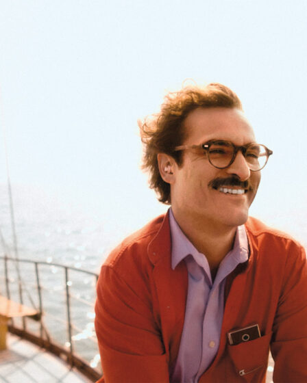 a man in glasses smiling on a boat